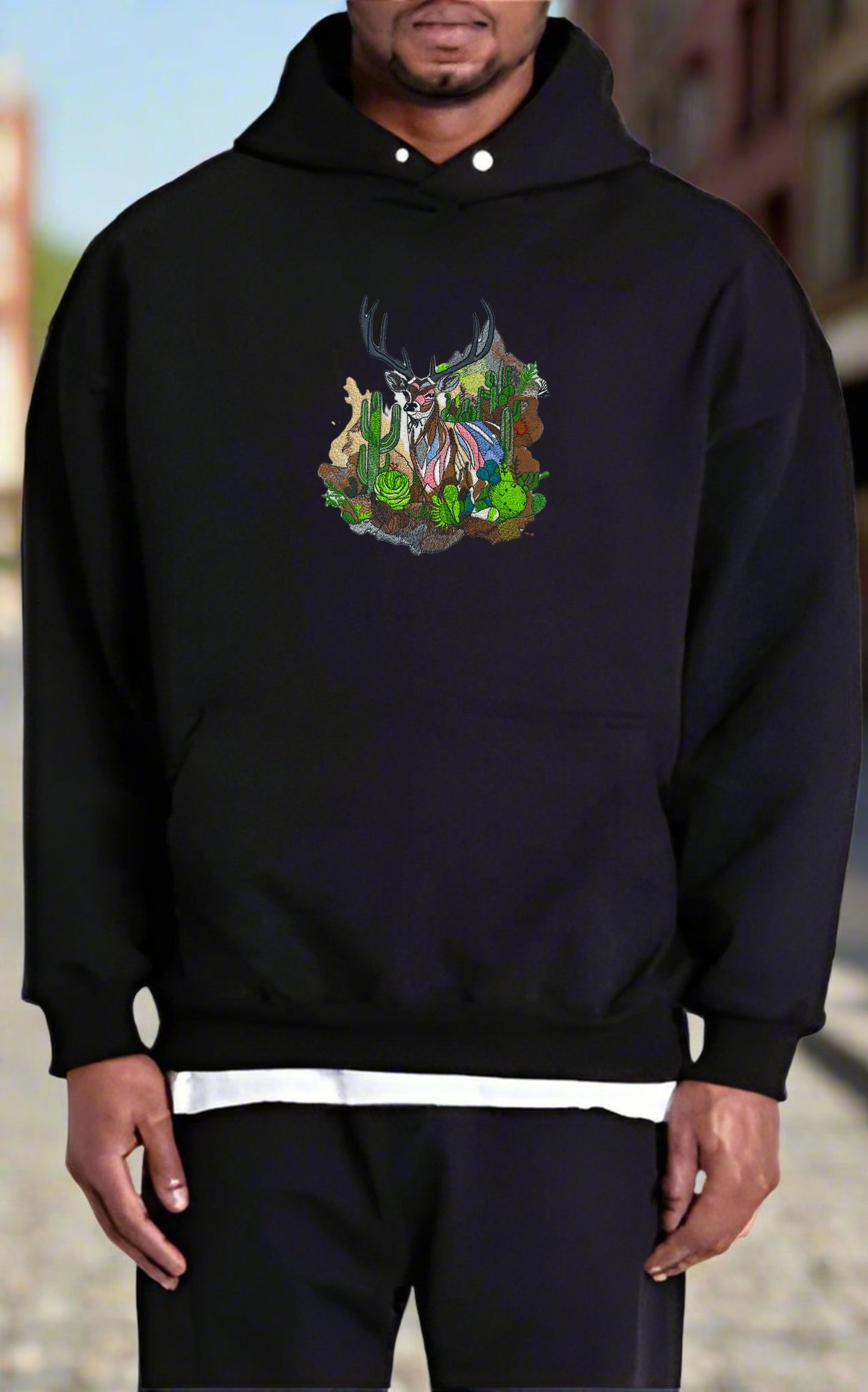 Embroidered hoodie featuring a mountain deer with Ombre antlers, surrounded by wildflowers and alpine pines, in a colorful design.