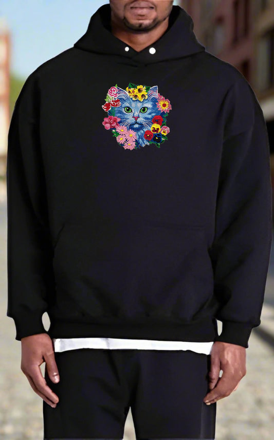 Person wearing a black hoodie with a colorful cat design on a blurred background