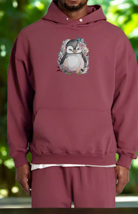 Maroon hoodie with a penguin design on a blurred green background
