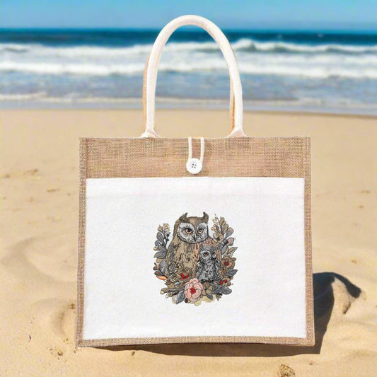 Jute bag with owl design on a sandy beach with ocean in the background