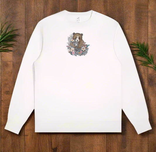 White long-sleeve shirt with a bear and floral design on a wooden surface
