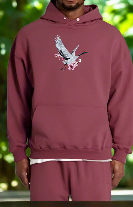 Maroon hoodie with a bird design on a blurred green background