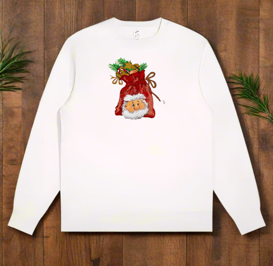White crewneck sweatshirt on wood background with an embroidered red gift bag featuring a Santa face and festive greenery.