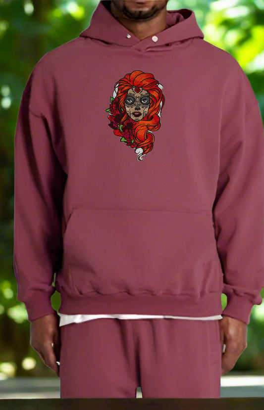 Maroon hoodie with a Sugar Skull Rose Girl Embroidery – Bold Artistic design on a blurred green background