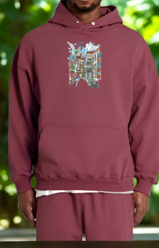 Maroon hoodie with a colorful graphic design on a blurred green background
