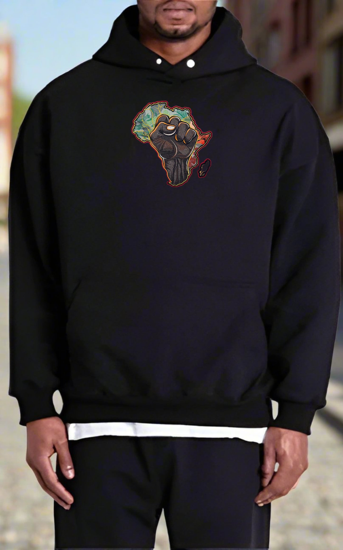 Person wearing a black hoodie with a African Pride Power Embroidery – Empowerment Statement design on a blurred background