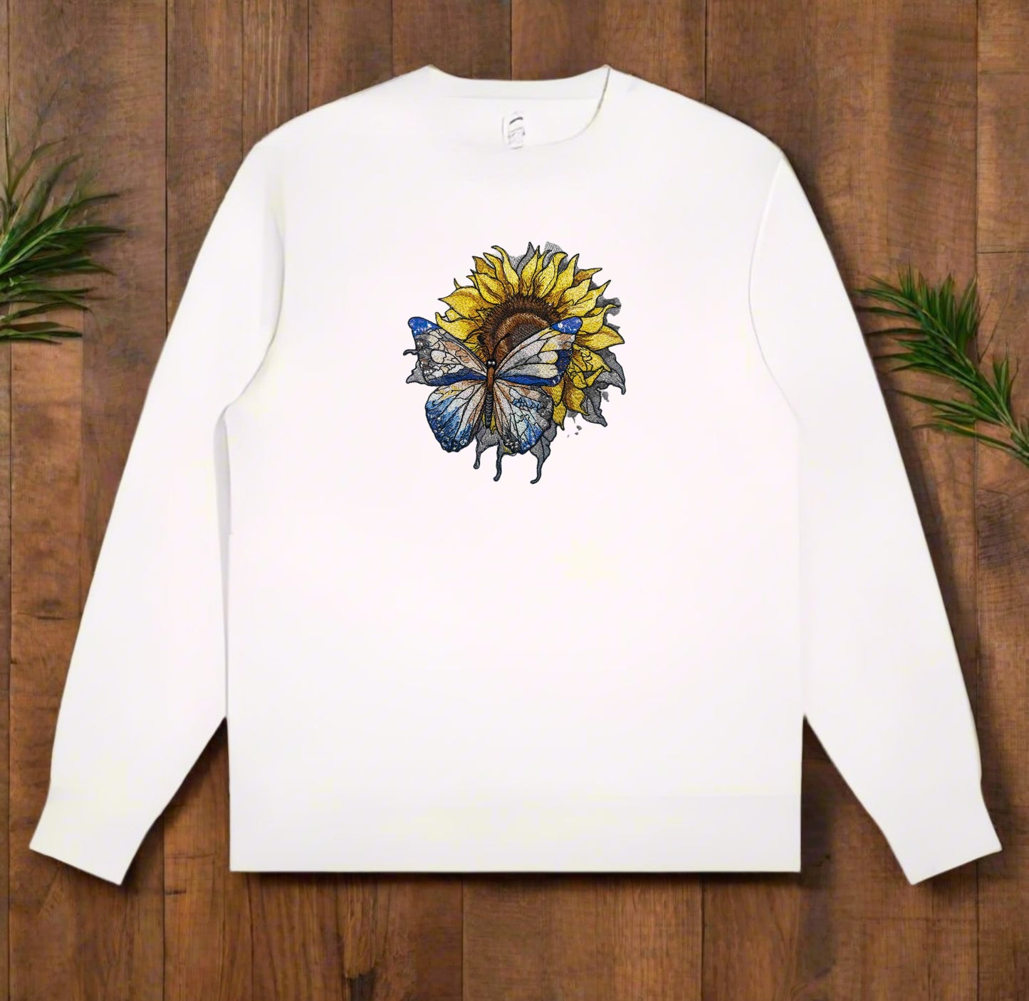 A detailed embroidery design of a sunflower with a butterfly, stitched in various colors on a white sweatshirt.