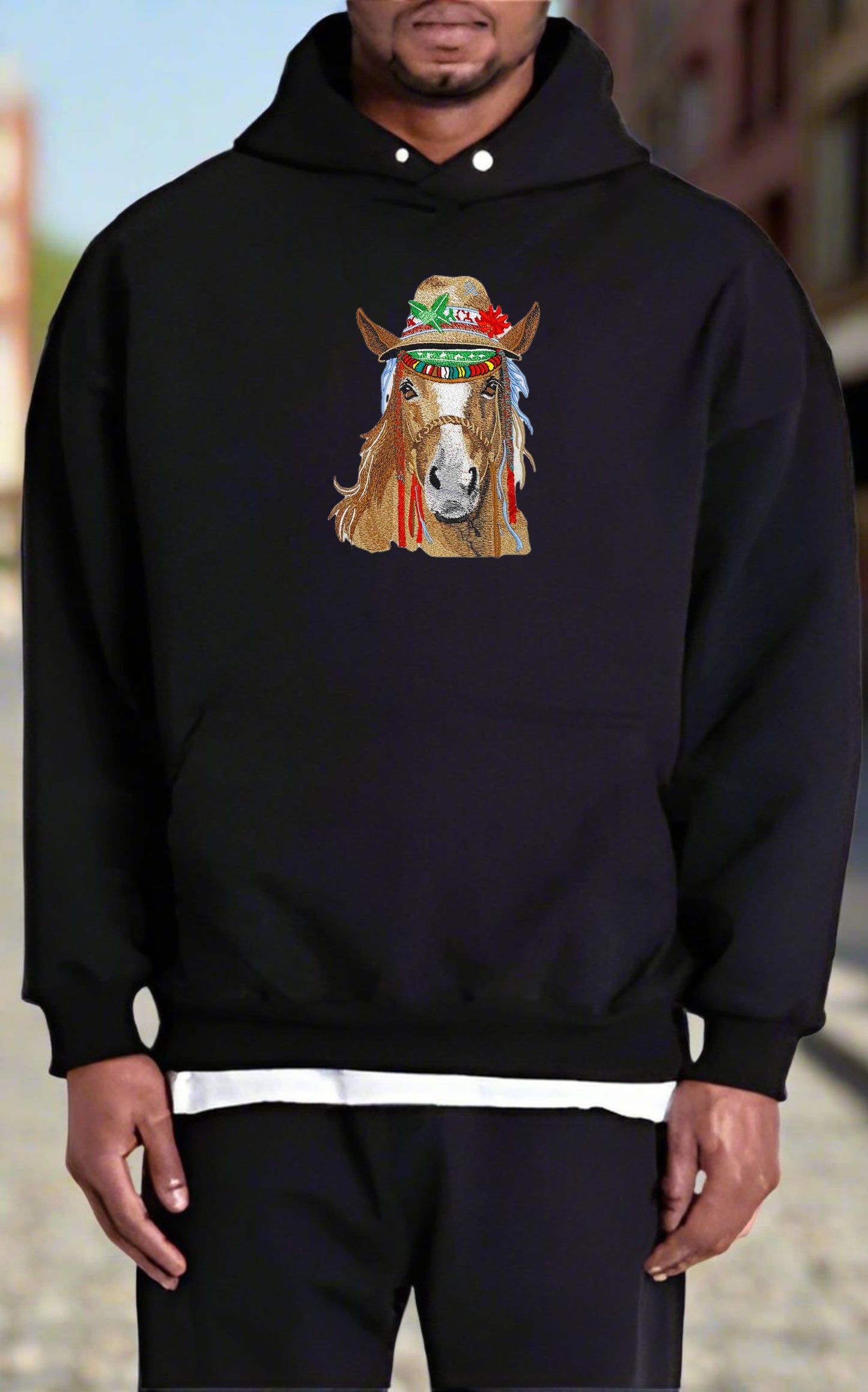 Person wearing a black hoodie with a horse graphic and colorful headgear.