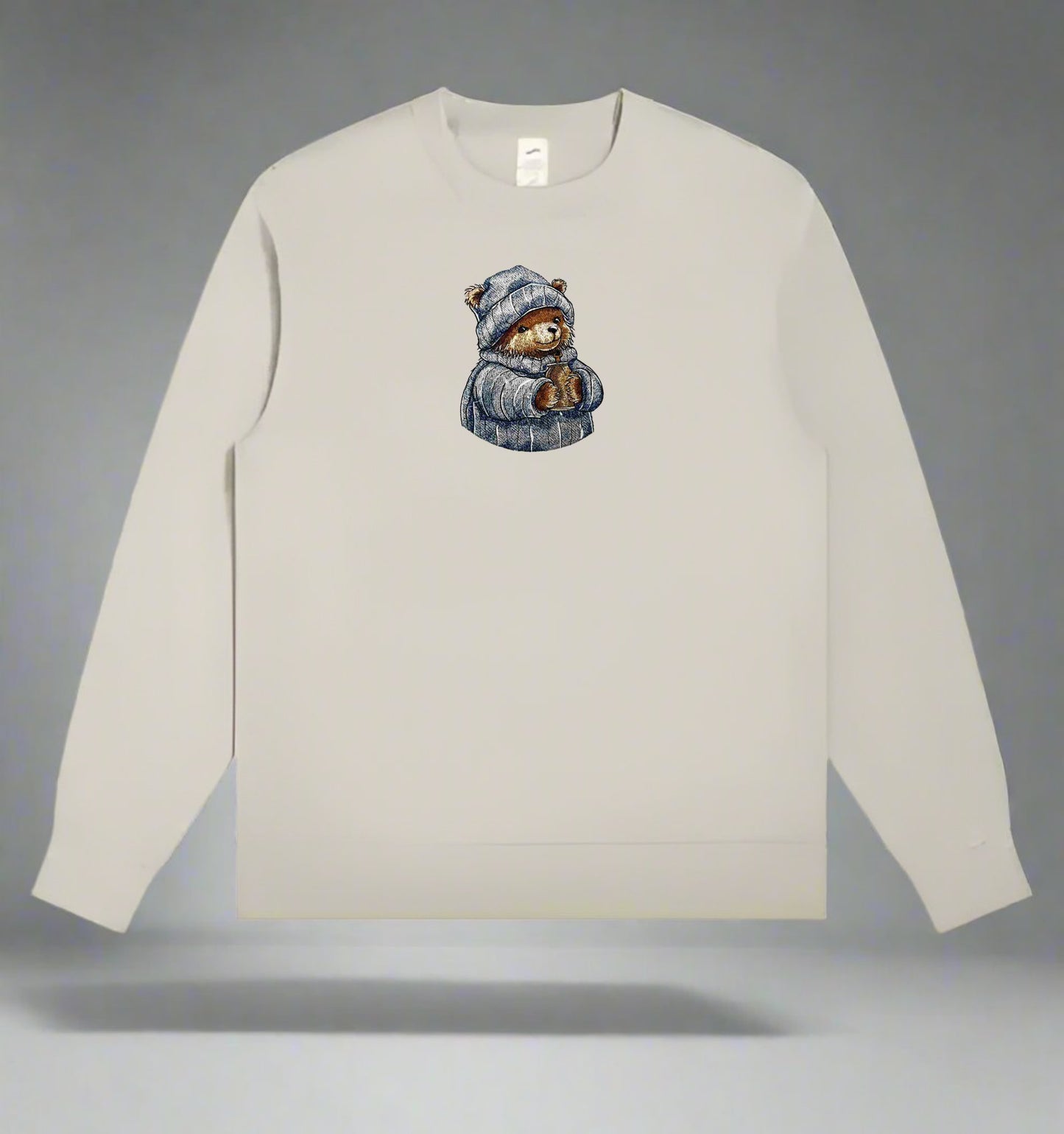 Beige long-sleeve shirt with a Cozy Cocoa Bear Embroidery – Snuggle Season on a gray background