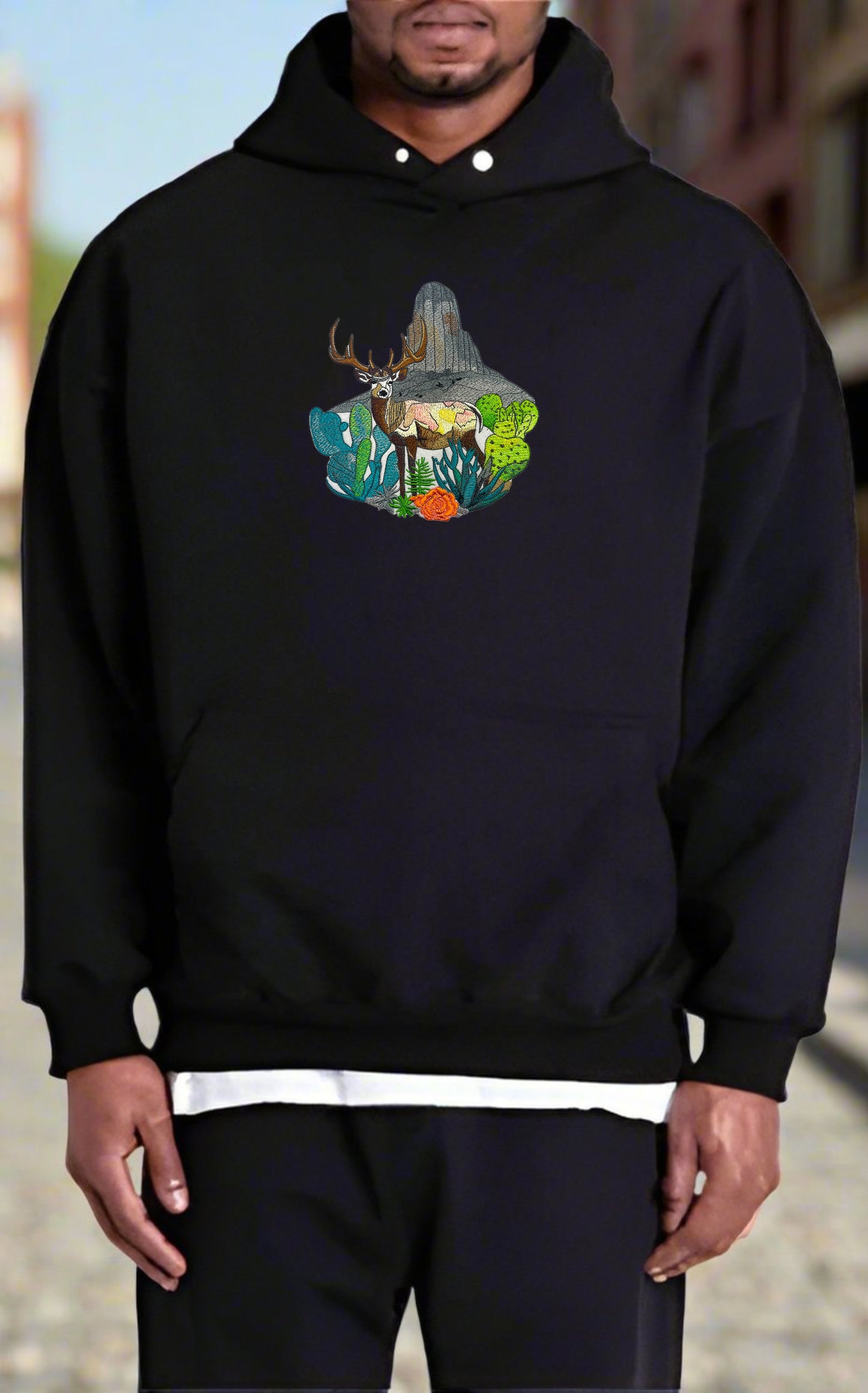 Embroidered hoodie featuring a mountain deer with a background of snow-capped mountains and greenery.
