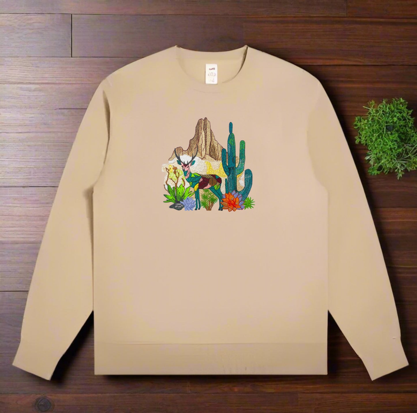 Embroidered khaki sweatshirt with a design featuring a mountain deer and cactus.