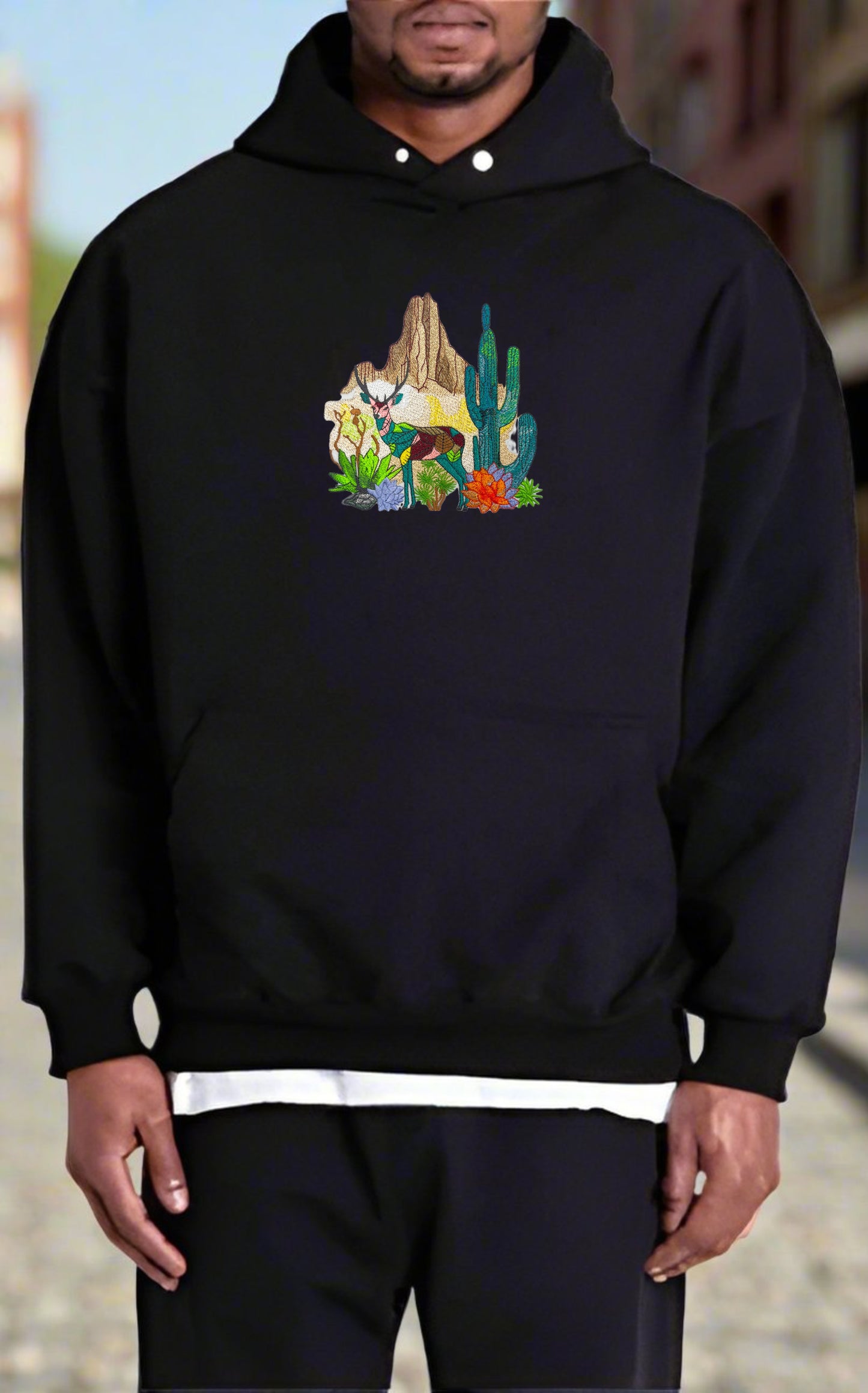 Embroidered hoodie featuring a mountain deer and cactus design on a white background.