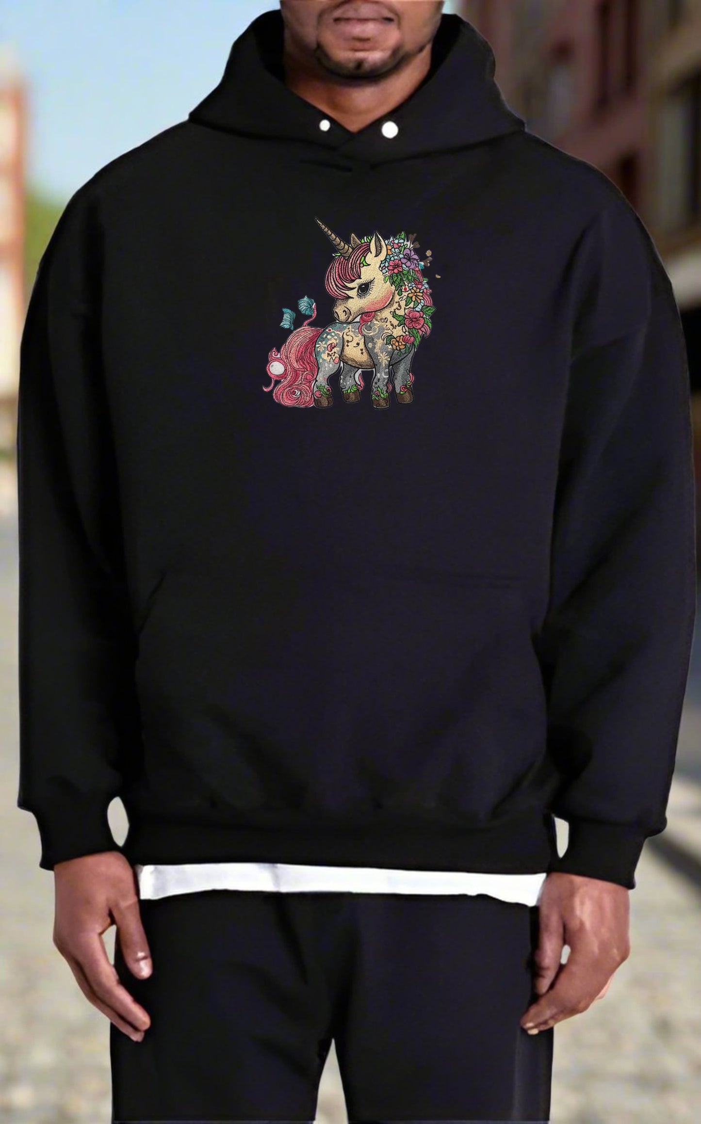 Person wearing a black hoodie with a colorful unicorn design on a blurred background