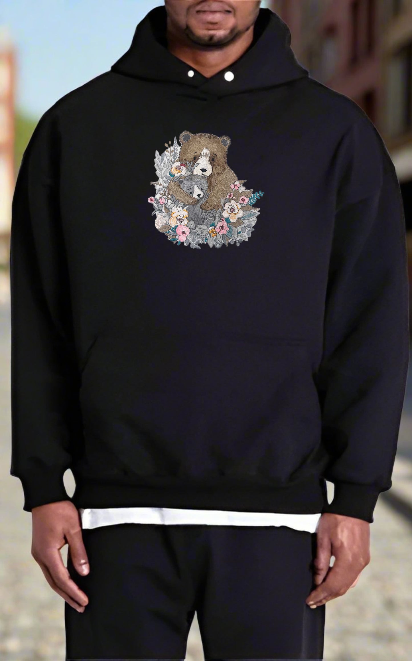 Person wearing a black hoodie with a bear and floral design.