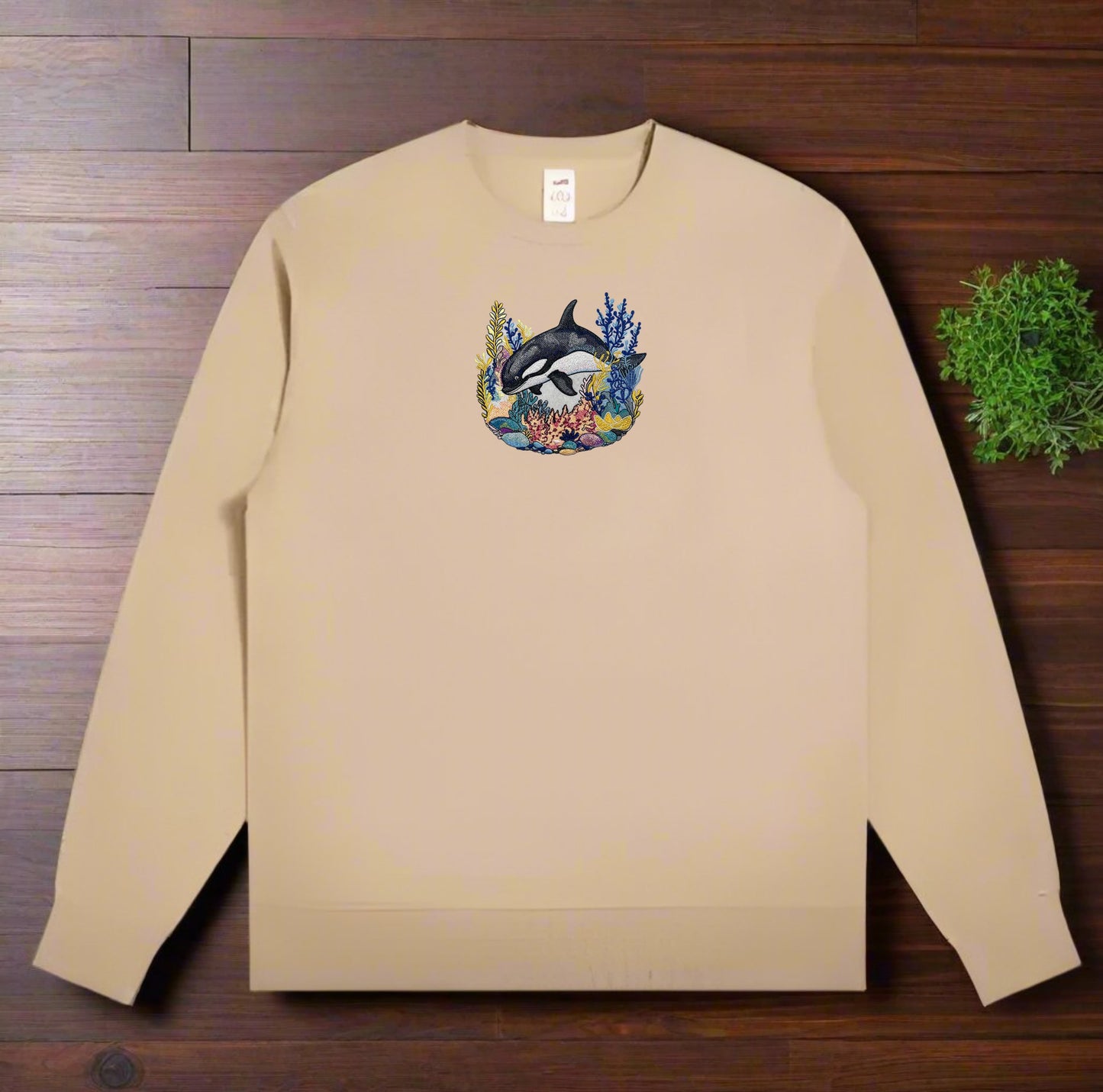 Beige sweatshirt with a dolphin design on a wooden surface