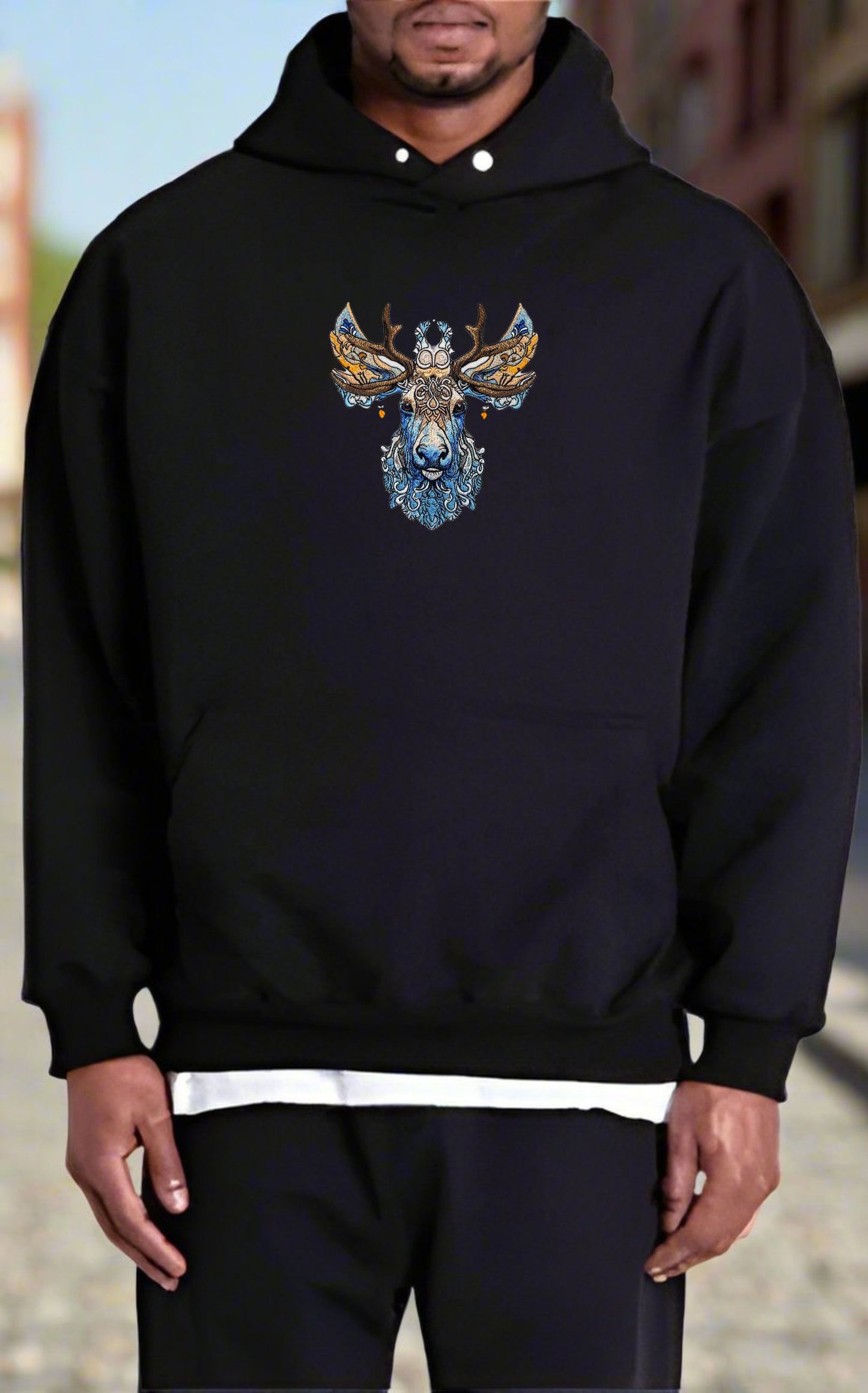 Embroidered hooded sweatshirt with a detailed image of a moose with antlers, surrounded by pine trees and a snowy mountain range.