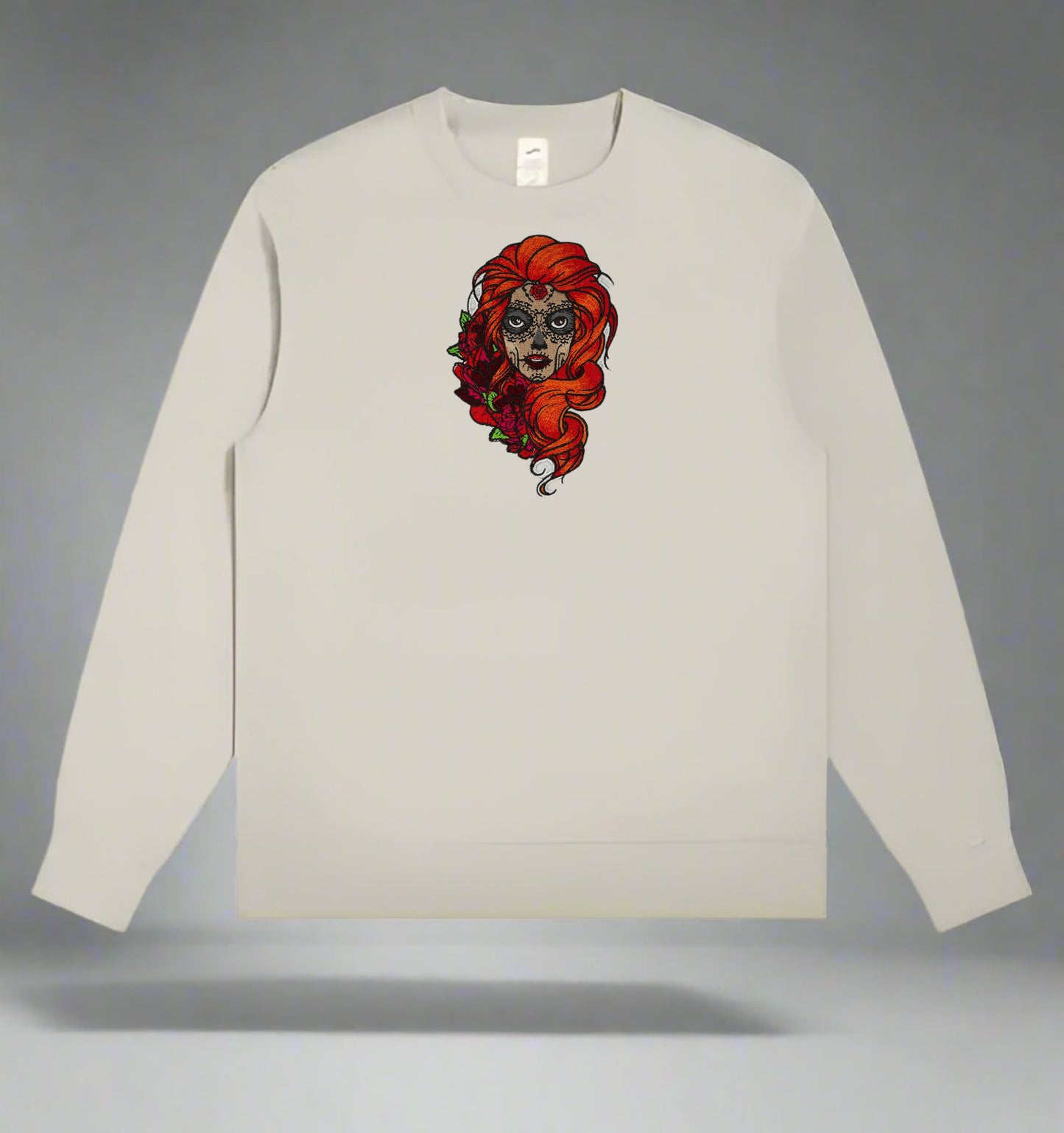 Beige long-sleeve shirt with a Sugar Skull Rose Embroidery – Artistic Heritage design of a woman with red hair on a gray background