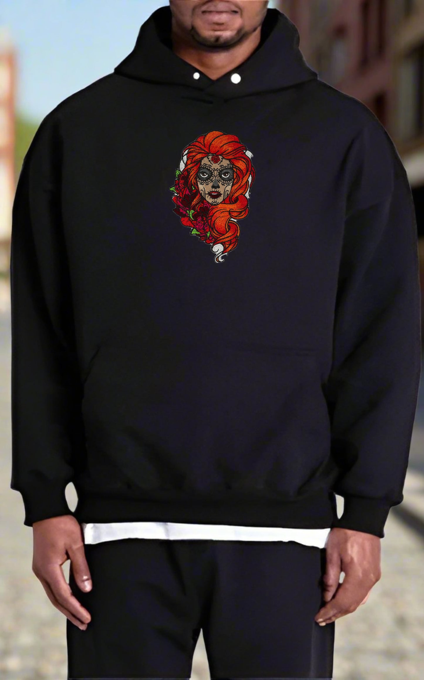 Person wearing a black hoodie with a Sugar Skull Rose Girl Embroidery – Bold Artistic design on a blurred background