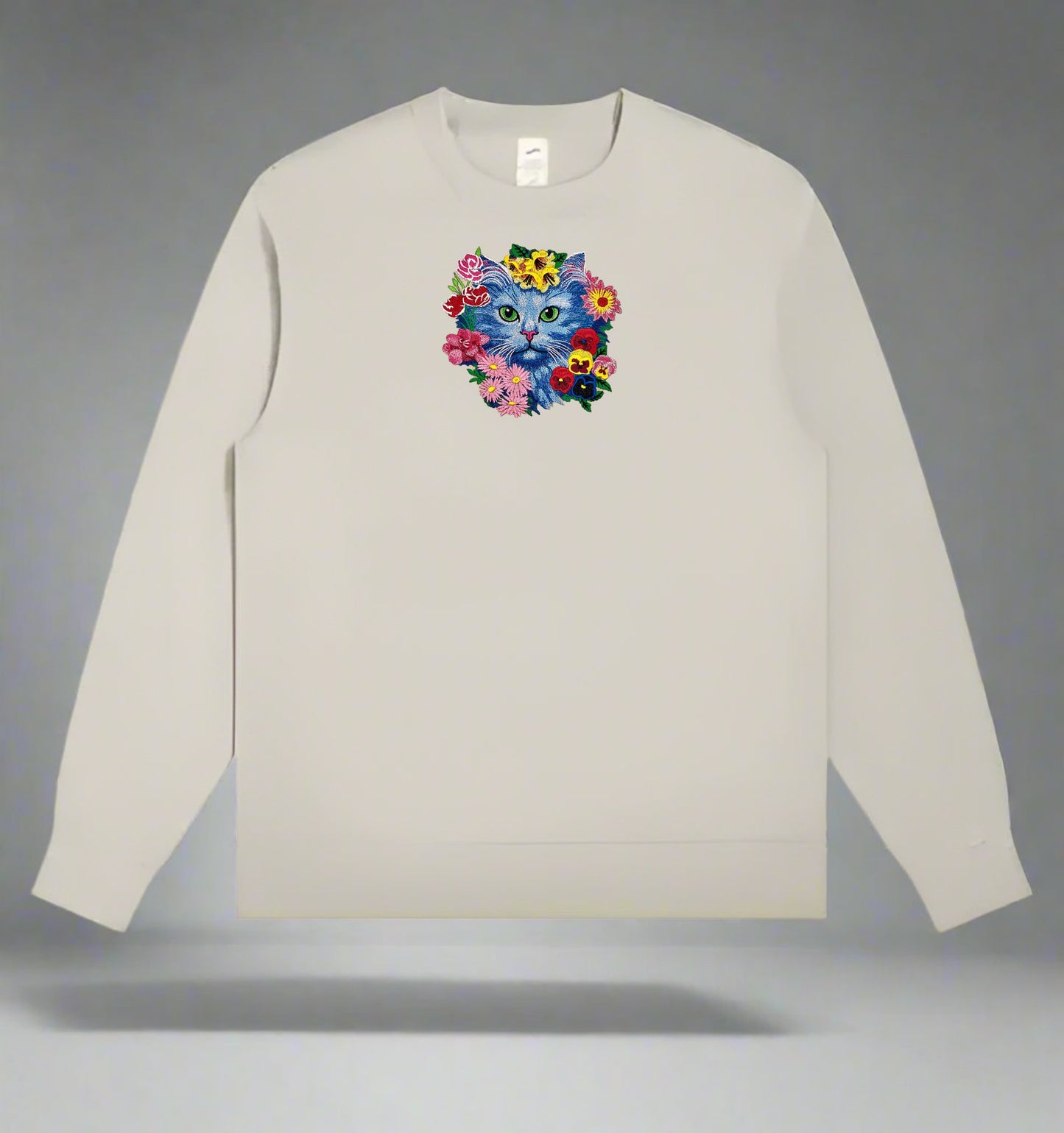 Beige long-sleeve sweatshirt with a colorful cat and flower design on a gray background