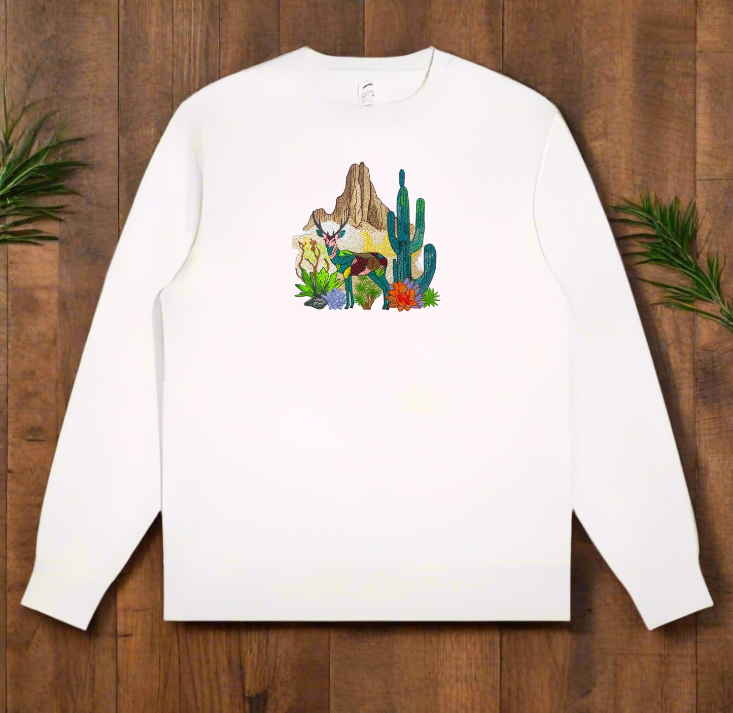 Embroidered white sweatshirt with a design featuring a mountain deer and cactus.