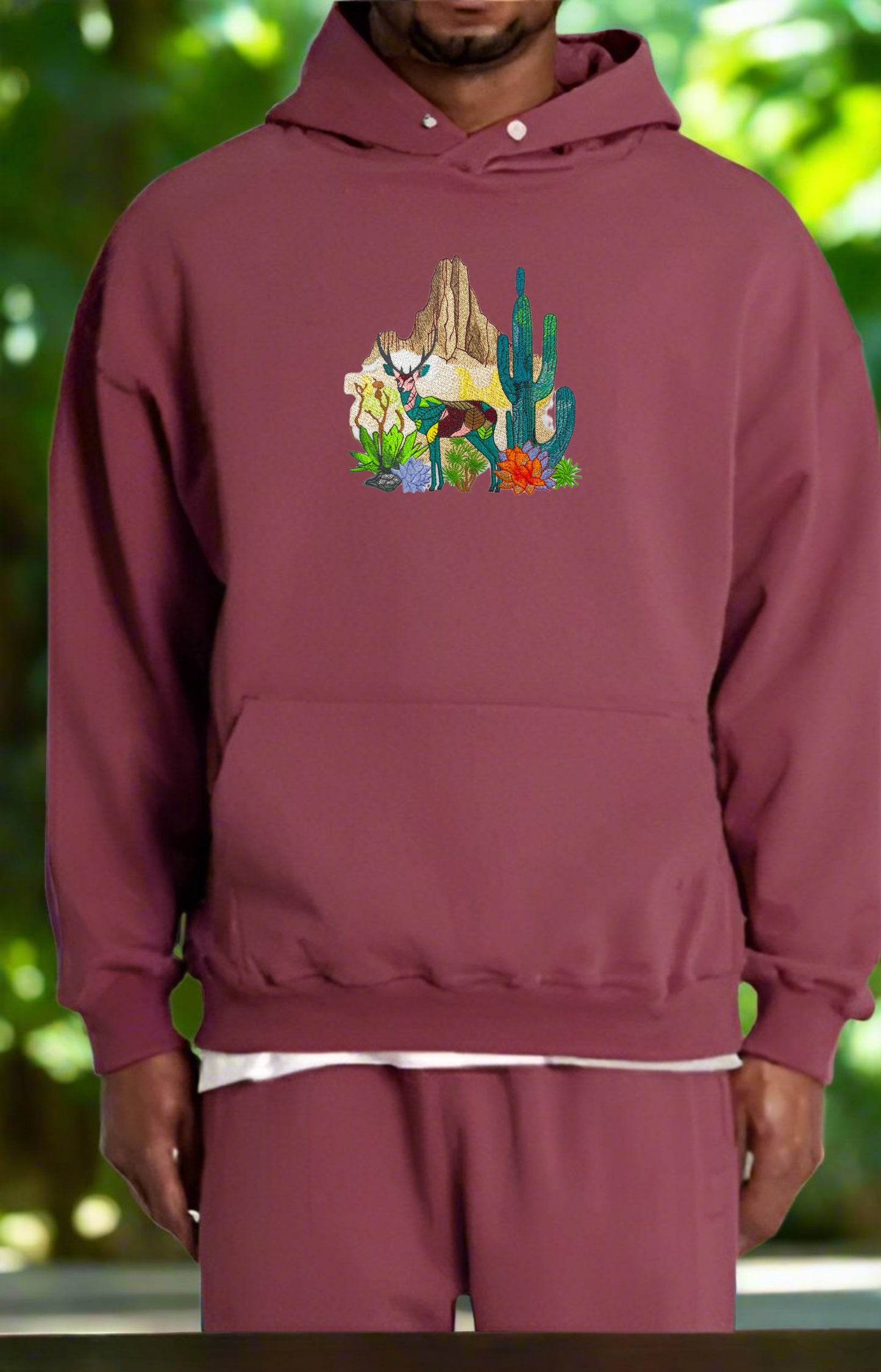 Embroidered hoodie featuring a mountain deer and cactus design on a white background.
