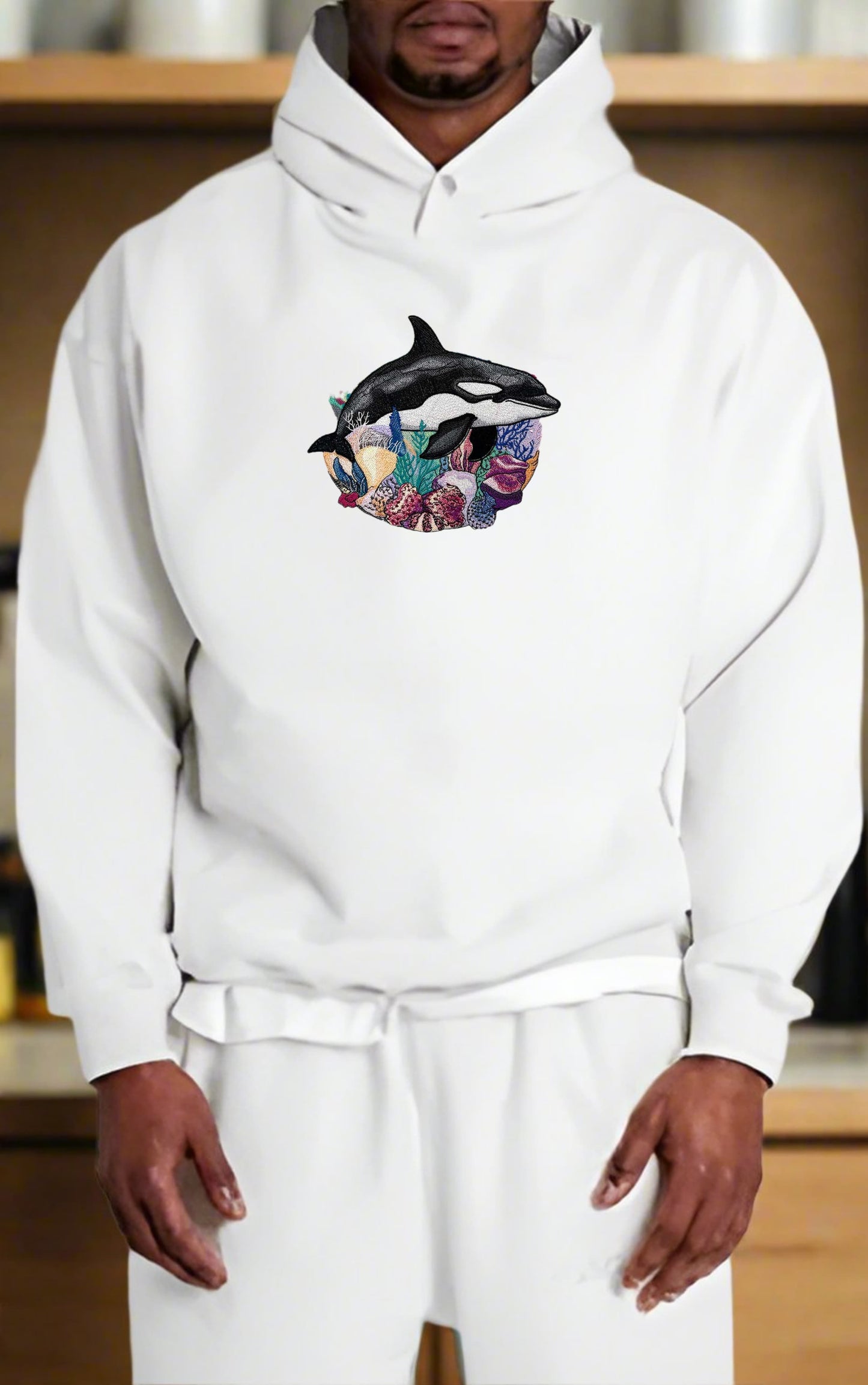 Person wearing a white hoodie with a colorful graphic design on a wooden shelf background