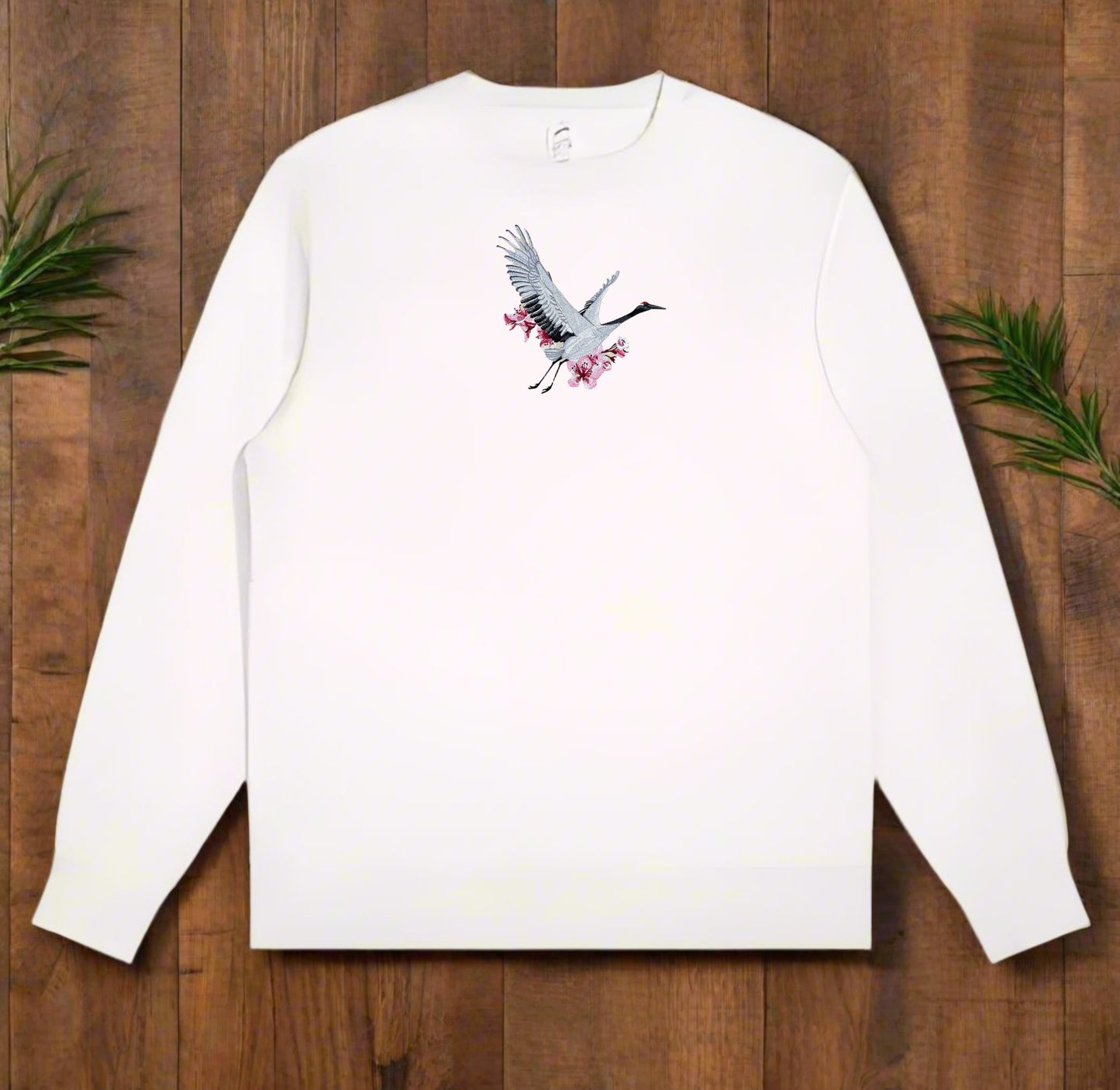 White long-sleeve shirt with a crane design on a wooden surface