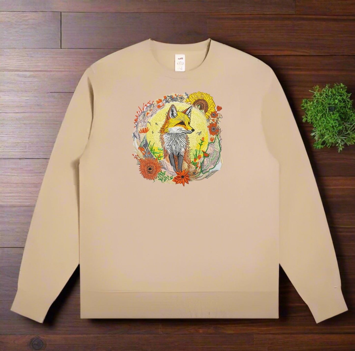 Embroidered crewneck sweatshirt with a design of a golden fox surrounded by floral patterns, predominantly in shades of yellow, green, and orange.