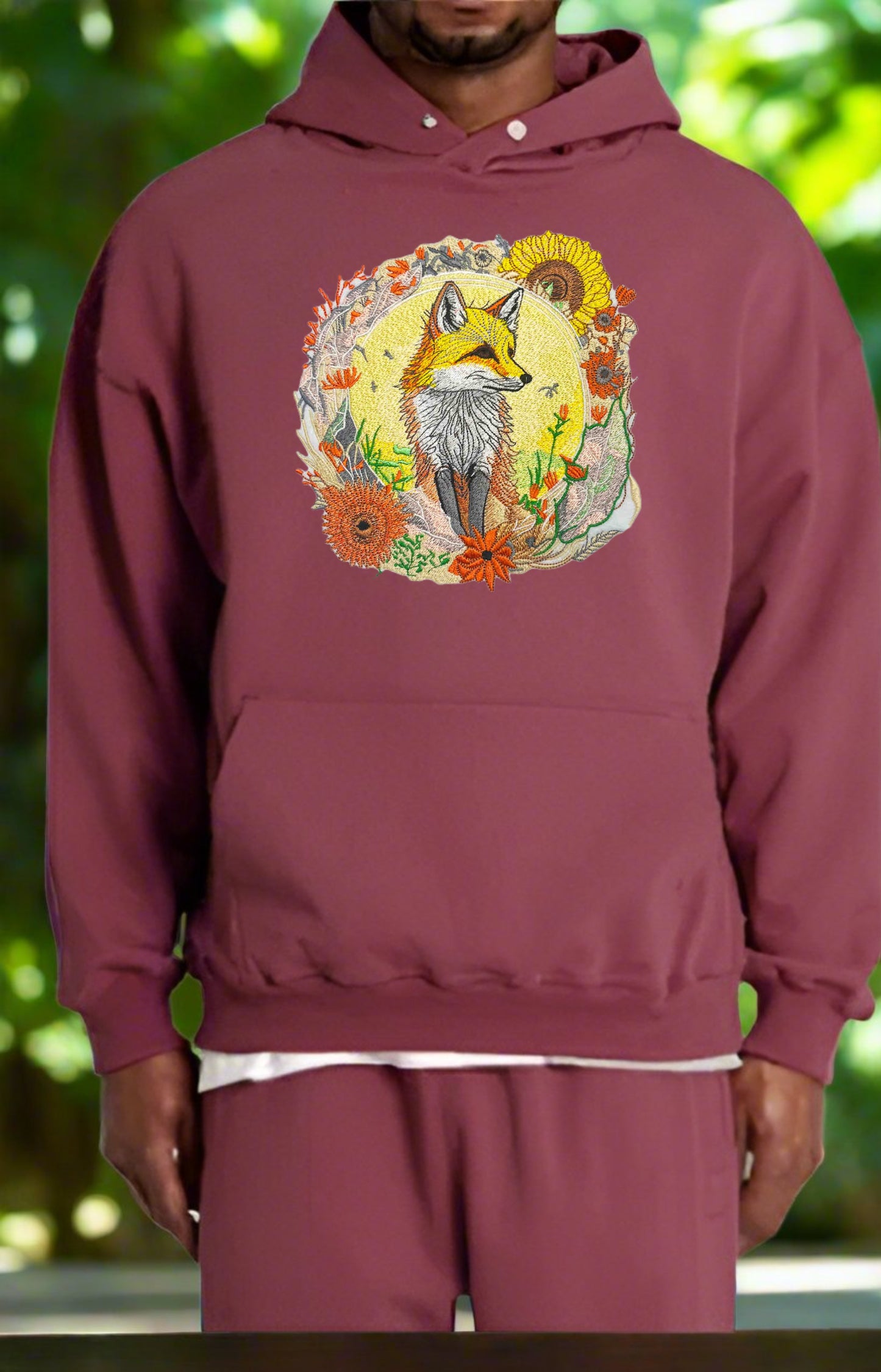 Embroidered hoodie featuring a golden fox surrounded by floral patterns, predominantly in shades of yellow, orange, and green.