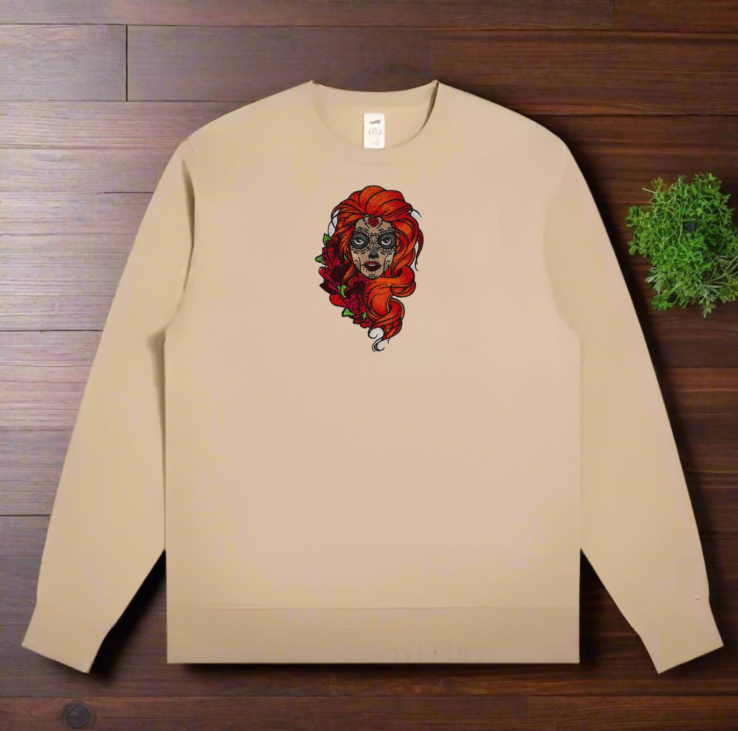 Beige sweatshirt with Sugar Skull Rose Embroidery – Artistic Heritage design on a wooden surface