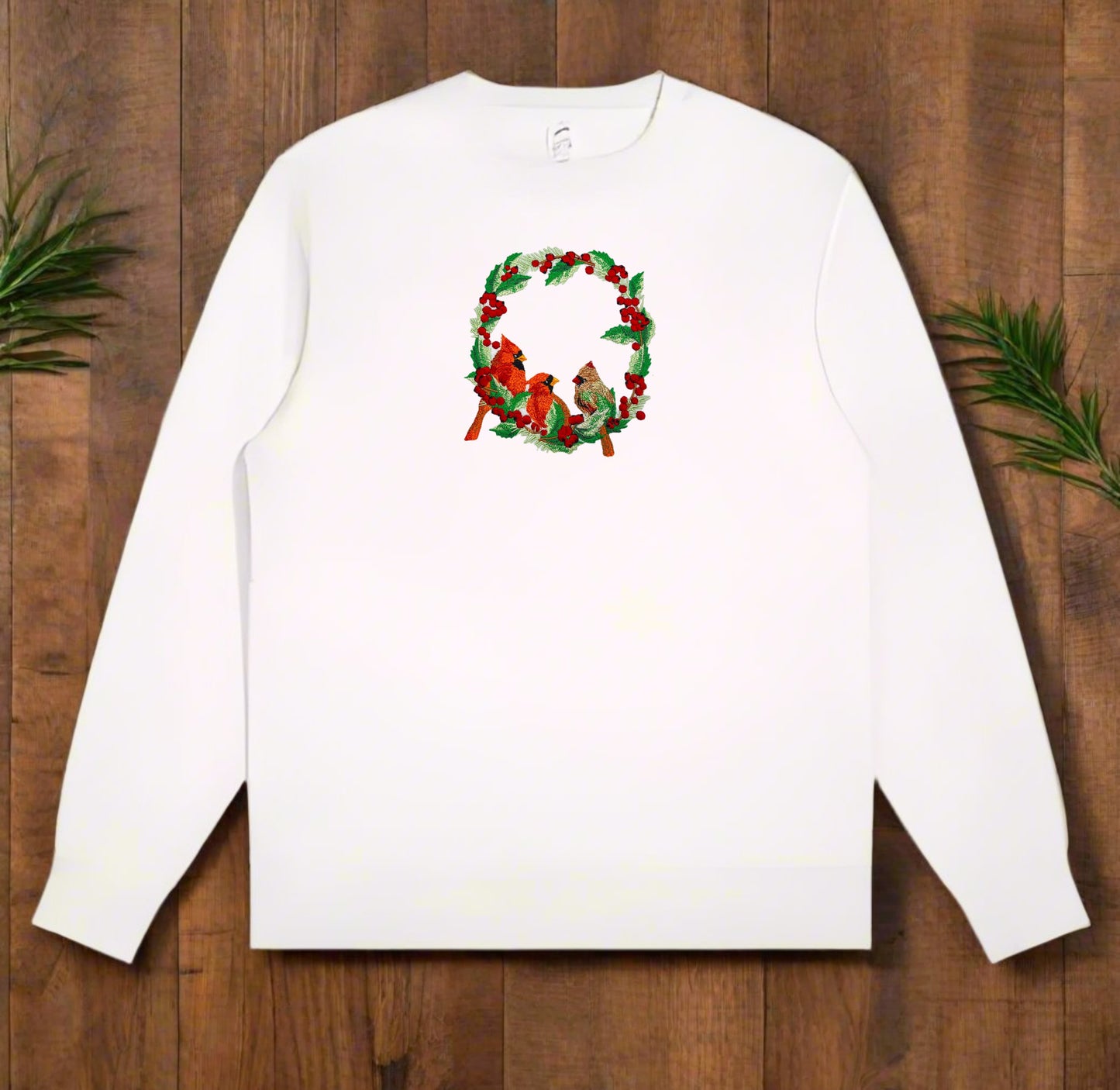 Embroidered design featuring two red cardinals among green foliage with red berries on a white background.
