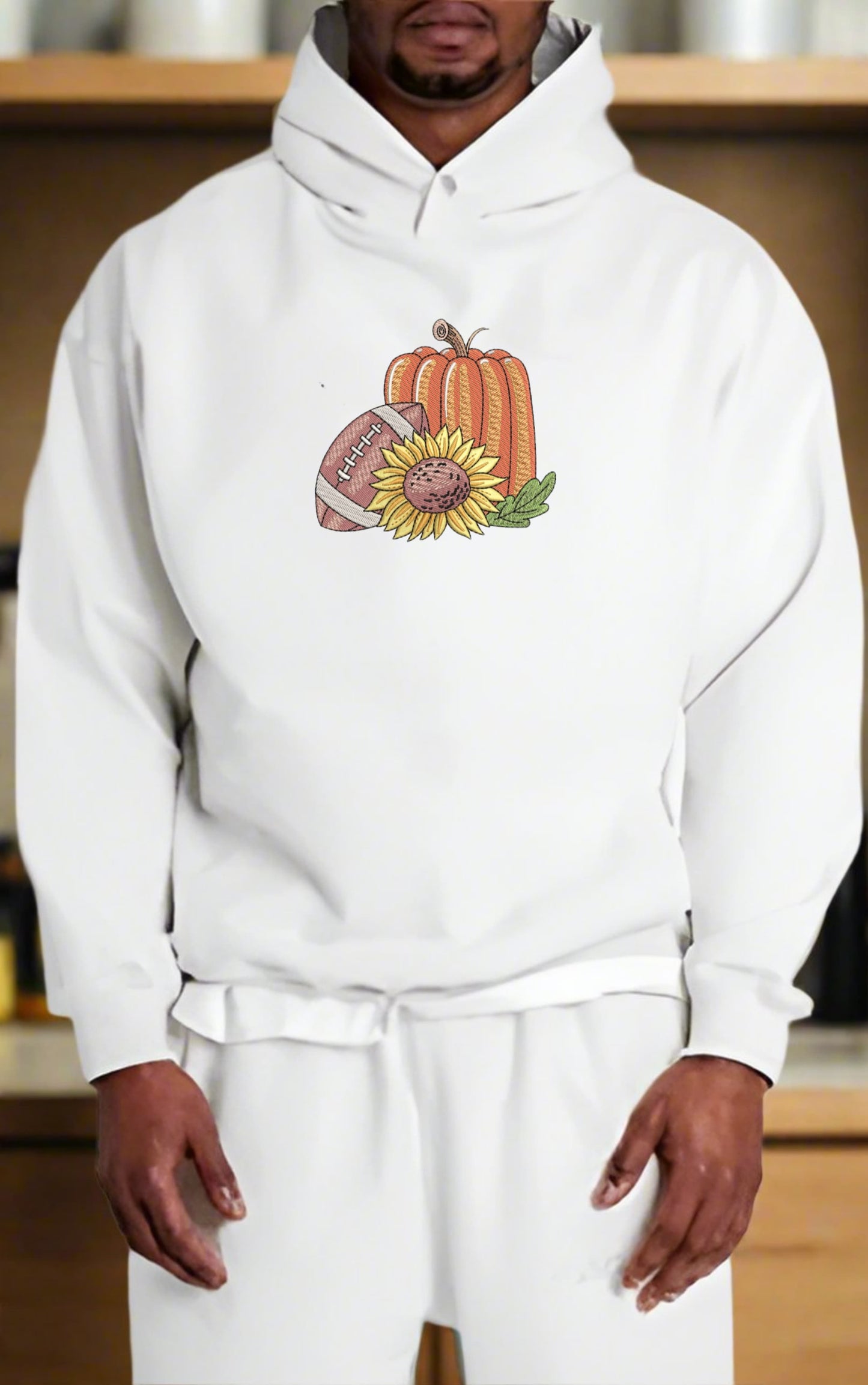 Person wearing a white hoodie with a pumpkin and sunflower design.