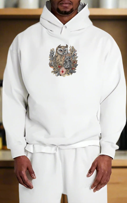 Person wearing a white hoodie with a colorful owl design on a wooden shelf background