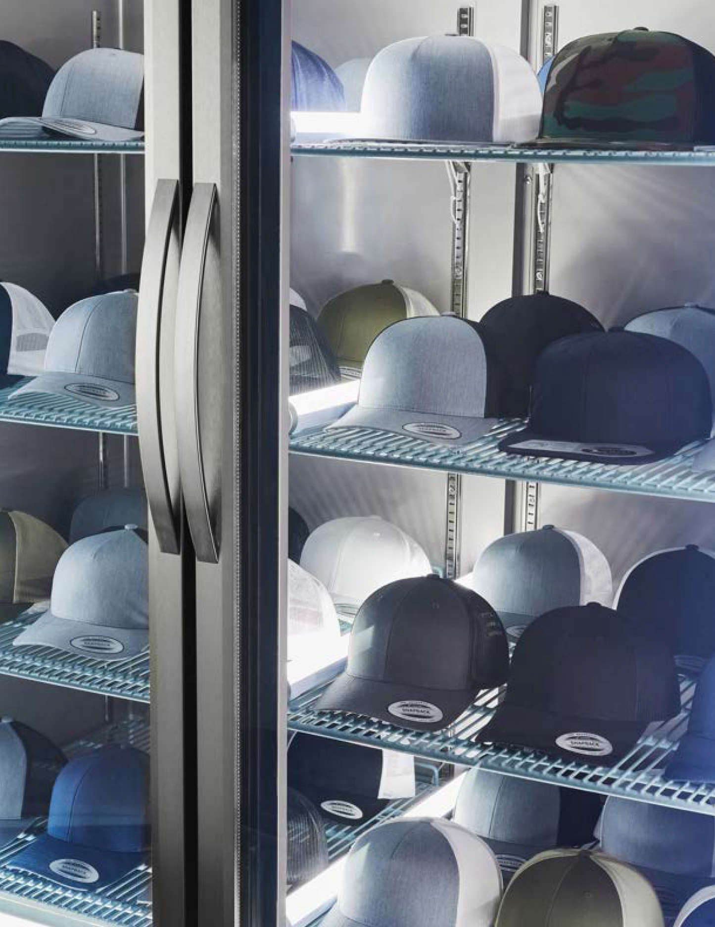 A glass display case containing multiple YP Classics 6606 Heritage baseball caps in various colors.