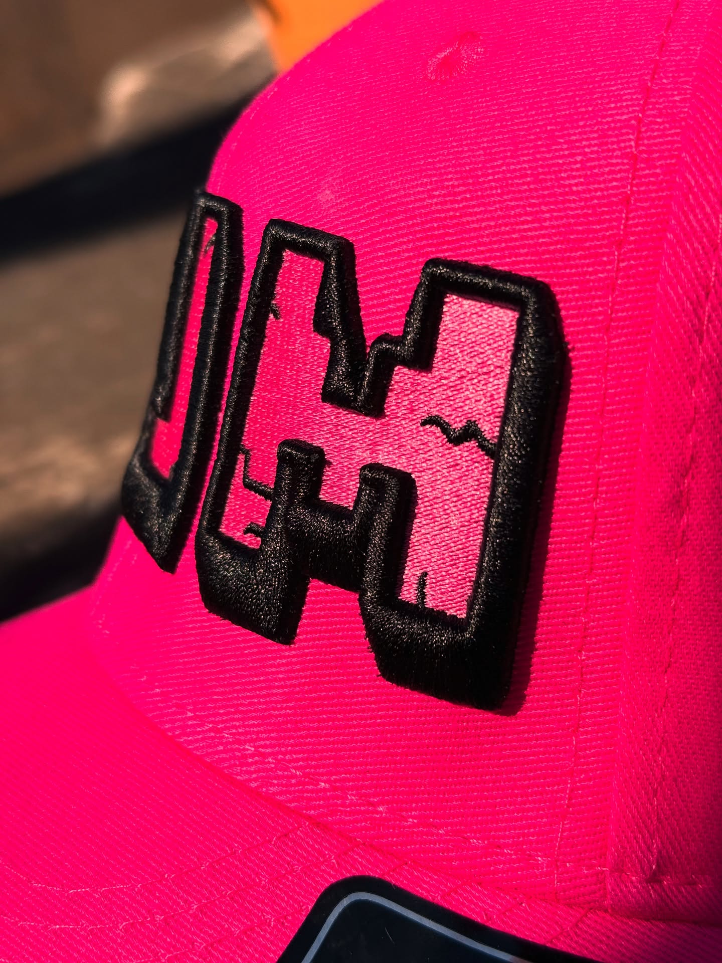 Close-up of a pink cap with a black logo on a blurred background