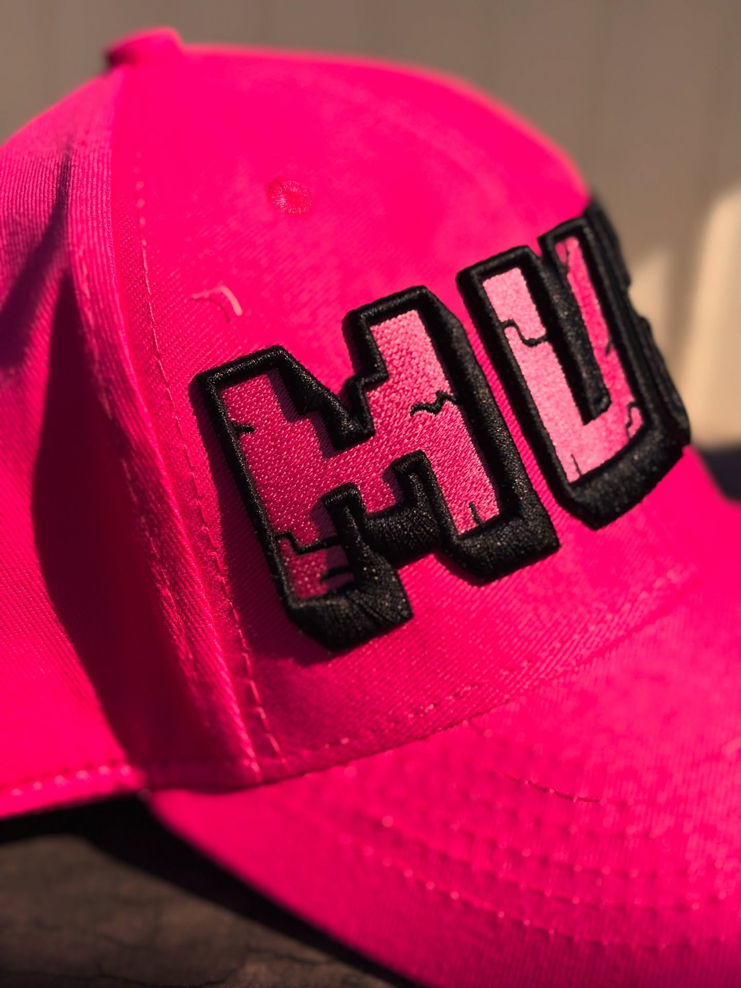 Pink cap with black 'MUM' logo on a blurred background