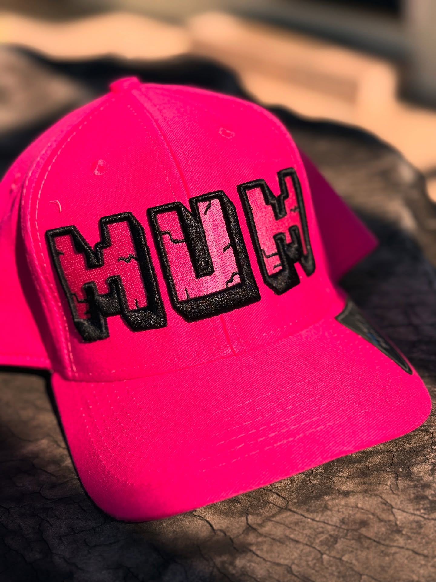 Pink cap with 'MUM' text on a textured surface