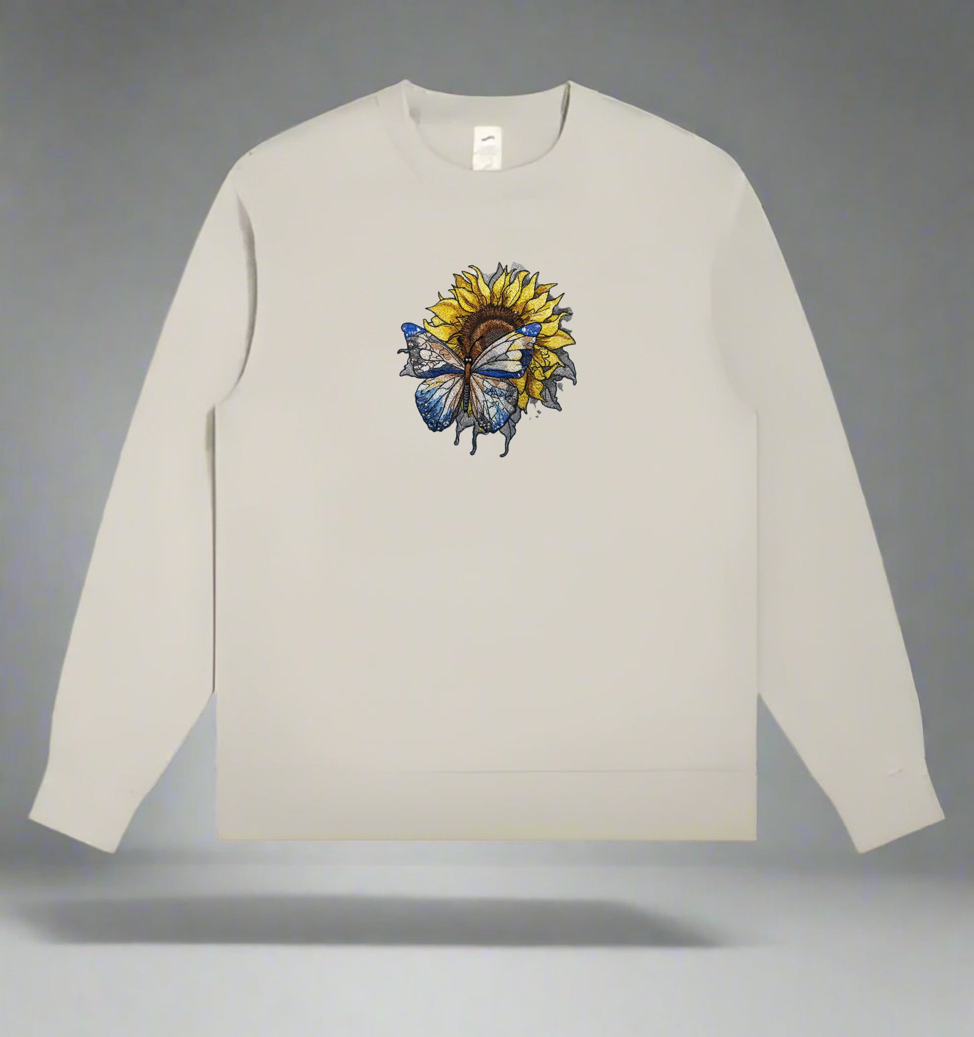 A detailed embroidery design of a sunflower with a butterfly, stitched in various colors on a mint green  sweatshirt.