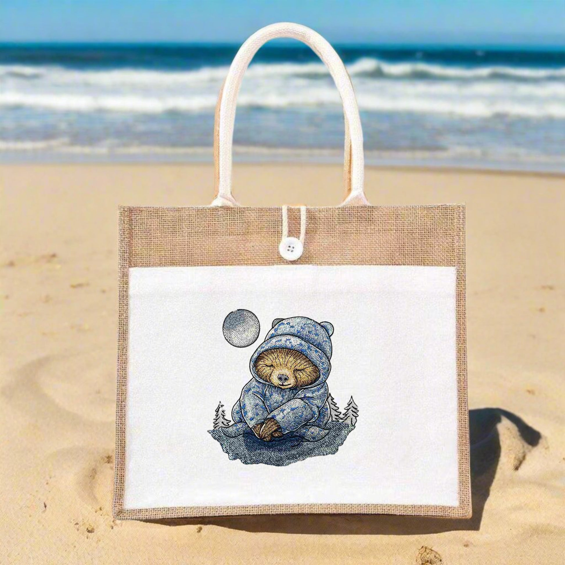 A tote bag with an embroidered design featuring a drowsy sloth in a night setting with stars and a crescent moon.