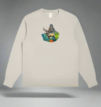 Embroidered crewneck sweatshirt with a design of a mountain deer surrounded by wildflowers and alpine pines against a rainbow-colored background.
