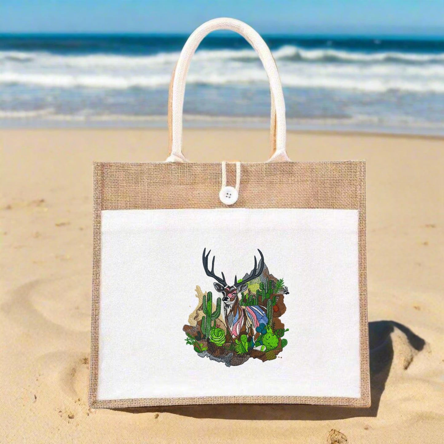 Embroidered jute tote bag featuring a mountain buck and cactus garden design.