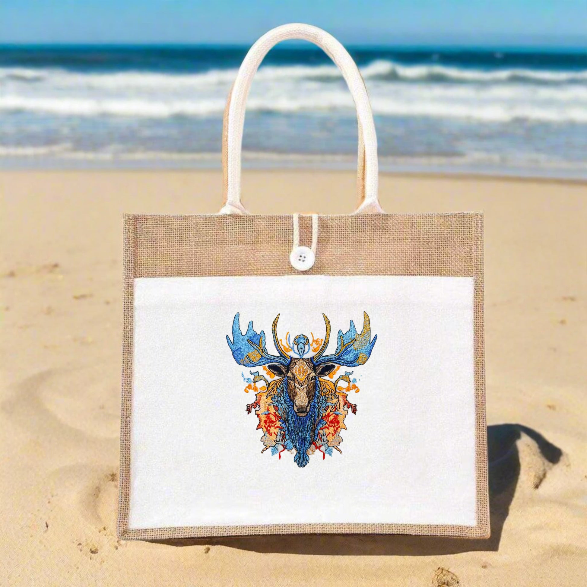 Embroidered jute tote bag featuring a detailed and colorful moose design amidst foliage and geometric patterns.