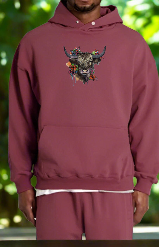 Maroon hoodie with a bull and floral design on a blurred green background