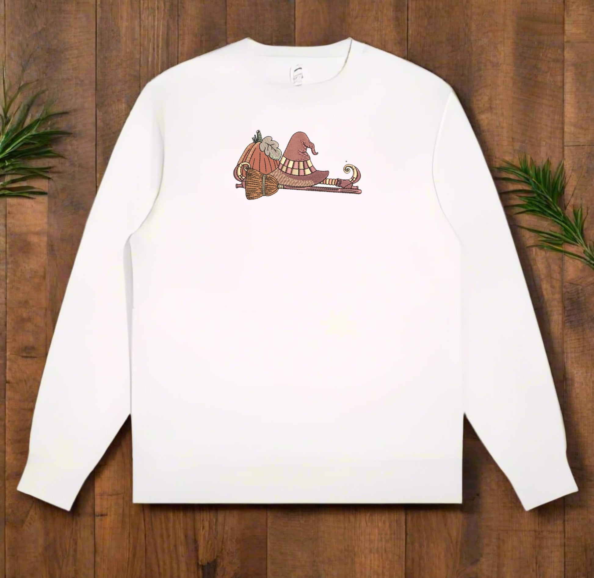 White long-sleeve sweatshirt with  If the Broom Fits Ride It Embroidery Design on a wooden surface