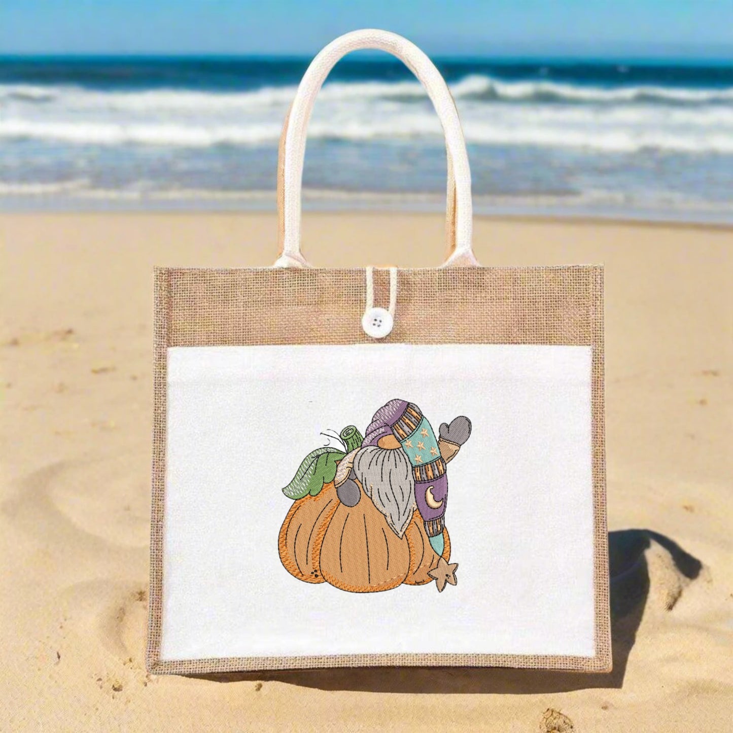 Jute bag with a cartoon gnome on a pumpkin design on a sandy beach.