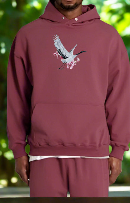 Maroon hoodie with a bird design on a blurred green background