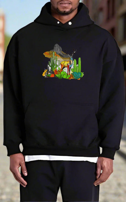 Embroidered hoodie featuring a mountain deer with antlers, surrounded by snow-dusted peaks and desert cacti, in a blend of earthy and glacial colors.