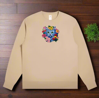 Beige sweatshirt with a colorful cat and flower design on a wooden surface.