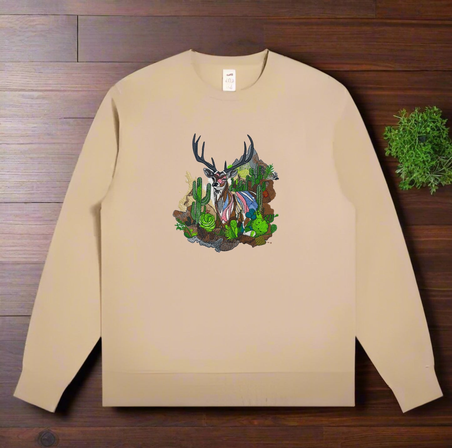 Embroidered crewneck sweatshirt with a design of a mountain deer among snow-dusted peaks and desert cacti.
