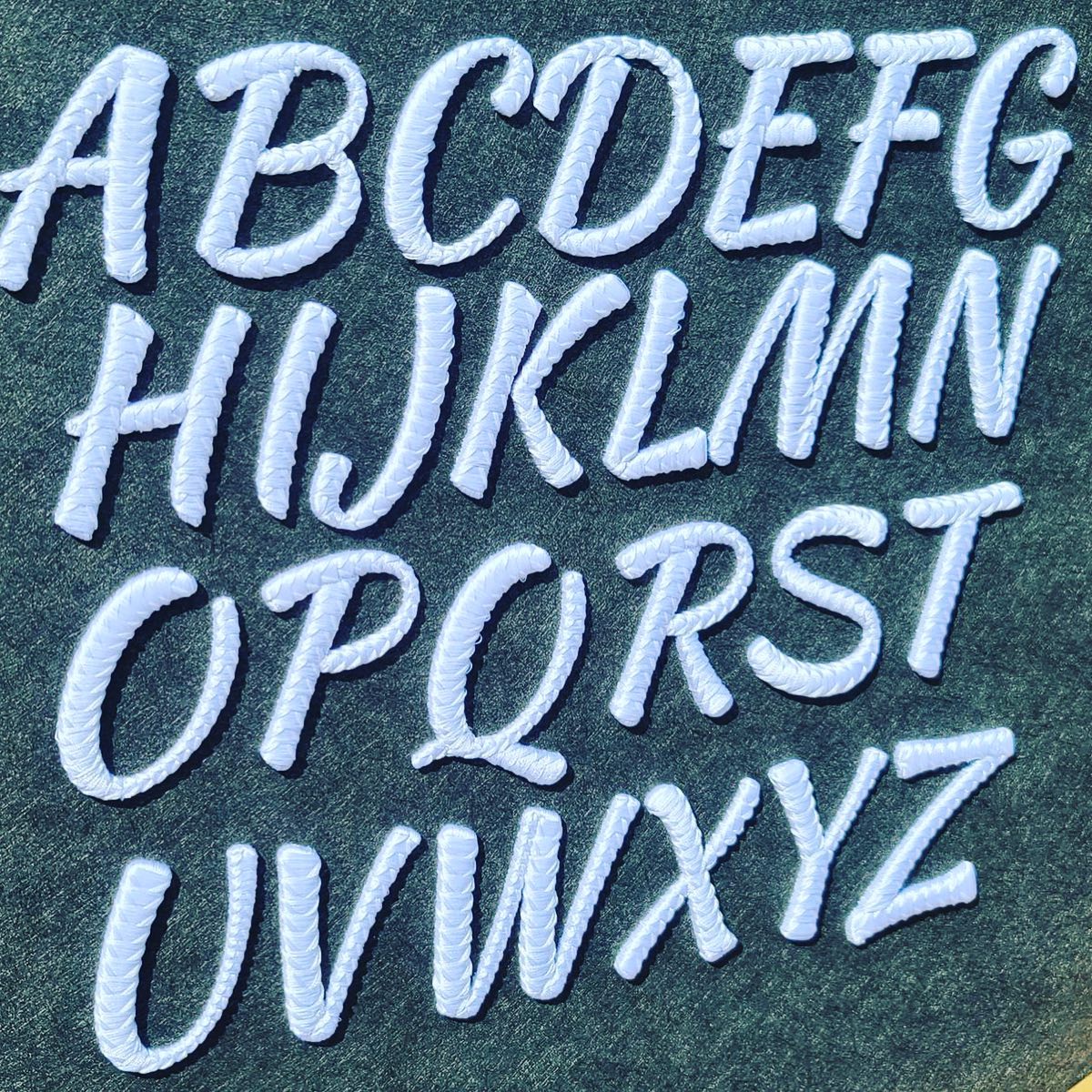 Embroidered alphabet letters on a dark fabric background